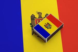 Moldova flag  is pictured on a matchbox that lies on a large flag photo