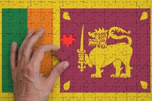 Sri Lanka flag  is depicted on a puzzle, which the man's hand completes to fold photo