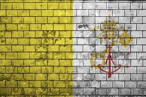 la bandera del estado de la ciudad del vaticano está pintada en una vieja pared de ladrillos foto