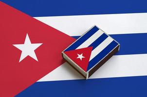 Cuba flag  is pictured on a matchbox that lies on a large flag photo