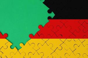 Germany flag  is depicted on a completed jigsaw puzzle with free green copy space on the left side photo