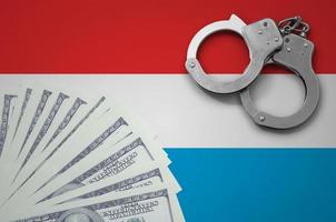 Luxembourg flag  with handcuffs and a bundle of dollars. The concept of illegal banking operations in US currency photo