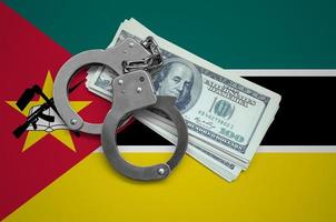 Mozambique flag  with handcuffs and a bundle of dollars. Currency corruption in the country. Financial crimes photo