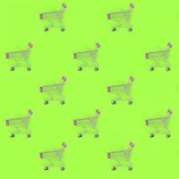 Shopping addiction, shopping lover or shopaholic concept. Many small empty shopping carts perform a pattern on a pastel colored paper background. Flat lay composition, top view photo