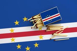 Cabo verde flag  is shown on an open matchbox, from which several matches fall and lies on a large flag photo