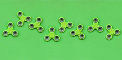 Many green fidget spinners lies on texture background of fashion pastel green color paper in minimal concept photo