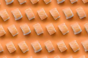 rollos filadelfia con salmón sobre fondo naranja. minimalismo vista superior patrón plano laico con comida japonesa foto