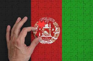 Afghanistan flag is depicted on a puzzle, which the man's hand completes to fold photo