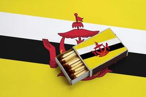 Brunei Darussalam flag  is shown in an open matchbox, which is filled with matches and lies on a large flag photo