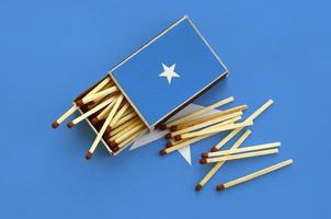 Somalia flag  is shown on an open matchbox, from which several matches fall and lies on a large flag photo