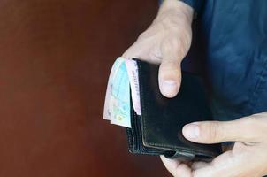 Man holds in hands black leather wallet with ukrainian money or thief who stole wallet full of money photo