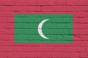 Maldives flag depicted in paint colors on old brick wall. Textured banner on big brick wall masonry background photo