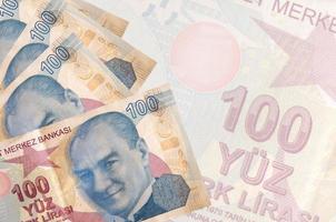 100 Turkish liras bills lies in stack on background of big semi-transparent banknote. Abstract business background photo