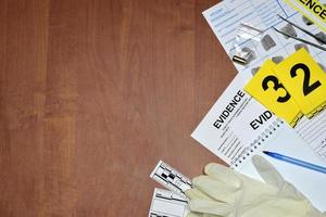 Paperwork during crime scene investigation process in csi laboratory. Evidence labels with fingerprint applicant and rubber gloves on vooden table photo