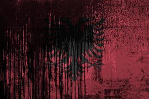 Albania flag depicted in paint colors on old and dirty oil barrel wall closeup. Textured banner on rough background photo