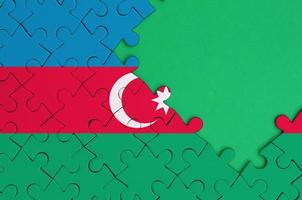 Azerbaijan flag  is depicted on a completed jigsaw puzzle with free green copy space on the right side photo