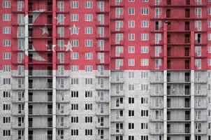 Singapore flag depicted in paint colors on multi-storey residental building under construction. Textured banner on brick wall background photo