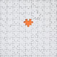 The texture of a white jigsaw puzzle in an assembled state with one missing element forming an orange space photo