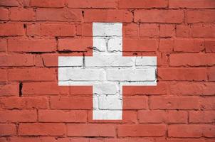 Switzerland flag is painted onto an old brick wall photo