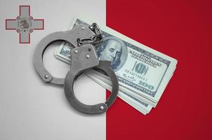 Malta flag  with handcuffs and a bundle of dollars. Currency corruption in the country. Financial crimes photo