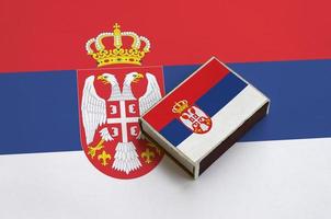 Serbia flag  is pictured on a matchbox that lies on a large flag photo