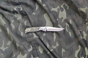 cuchillo militar en ropa de camuflaje del ejército de cerca. fondo con espacio de copia para el diseño de servicios militares o especiales foto