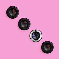 A few camera lenses with a closed aperture lie on texture background of fashion pastel pink color paper in minimal concept. Abstract trendy pattern photo