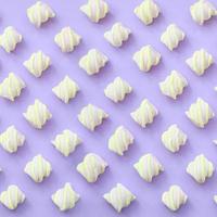 Colorful marshmallow laid out on violet paper background. pastel creative textured pattern. minimal photo