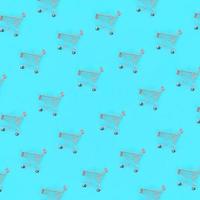 Shopping addiction, shopping lover or shopaholic concept. Many small empty shopping carts perform a pattern on a pastel colored paper background. Flat lay composition, top view photo