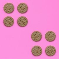 Pattern of a brown biscuits on a pink background. Trendy minimal concept of food and dessert. Abstract flat lay, top view photo
