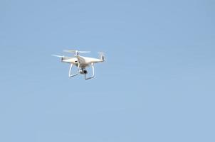 Big white drone hovering in a bright cloudless blue sky photo