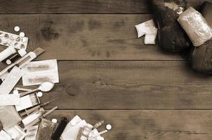 A lot of narcotic pills and devices for the preparation of drugs lie on an old wooden table photo