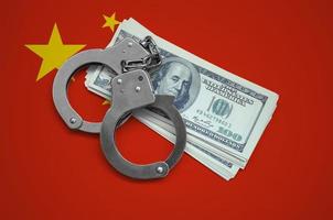 China flag  with handcuffs and a bundle of dollars. Currency corruption in the country. Financial crimes photo