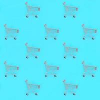 Shopping addiction, shopping lover or shopaholic concept. Many small empty shopping carts perform a pattern on a pastel colored paper background. Flat lay composition, top view photo