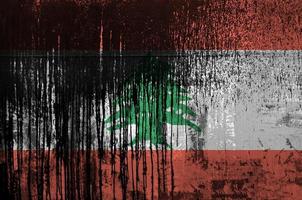 Lebanon flag depicted in paint colors on old and dirty oil barrel wall closeup. Textured banner on rough background photo