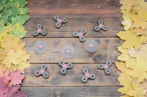 Several spinners among the many yellowing fallen autumn leaves on the background surface of natural wooden boards of dark brown color photo