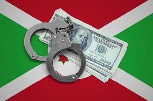 Burundi flag  with handcuffs and a bundle of dollars. Currency corruption in the country. Financial crimes photo