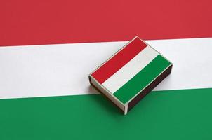 Hungary flag  is pictured on a matchbox that lies on a large flag photo