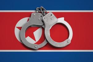 North Korea flag  and police handcuffs. The concept of observance of the law in the country and protection from crime photo