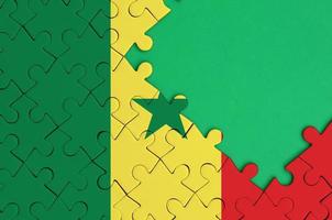 Senegal flag  is depicted on a completed jigsaw puzzle with free green copy space on the right side photo