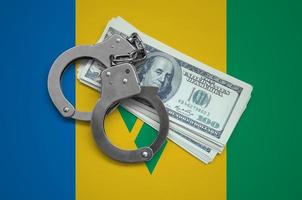 Saint Vincent and the Grenadines flag  with handcuffs and a bundle of dollars. Currency corruption in the country. Financial crimes photo