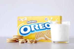 TERNOPIL, UKRAINE - MAY 28, 2022 Oreo golden crispy cookies with glass of milk on white background. The brand Oreo is owned by company Mondelez international photo