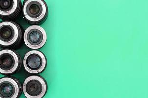 Several photographic lenses lie on a bright turquoise background. Copy space photo