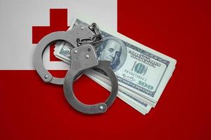 Tonga flag  with handcuffs and a bundle of dollars. Currency corruption in the country. Financial crimes photo