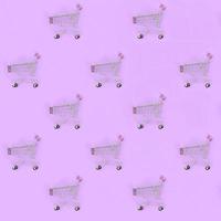 Shopping addiction, shopping lover or shopaholic concept. Many small empty shopping carts perform a pattern on a pastel colored paper background. Flat lay composition, top view photo