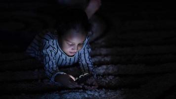 niña jugando con smartphone en la oscuridad