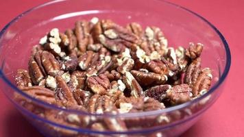 Pecans fall into clear glass bowl video