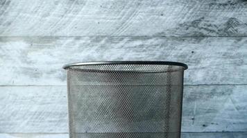 Wire mesh trash bin in front of a wooden wall video