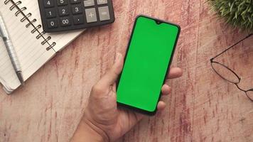 Smartphone in hand on wood desk, a calculator and notebook video