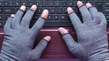 personne avec des types de gants sans doigts sur le clavier de l'ordinateur video